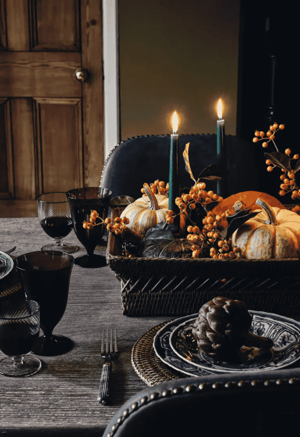 A cozy table setting adorned with flickering candles and vibrant pumpkins, perfect for autumn gatherings and festive dinners.